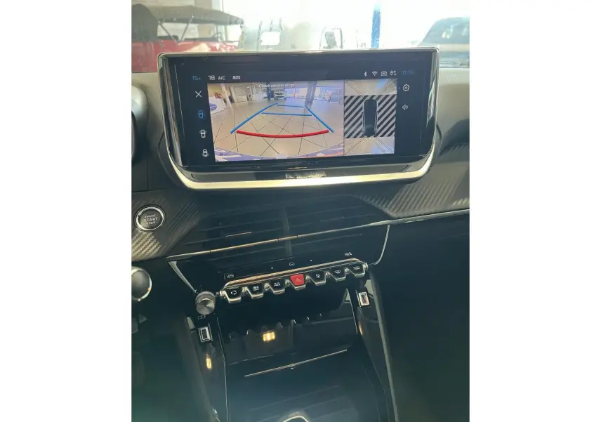 Vue rapprochée de la console centrale et écran tactile du Peugeot 208 1.2 essence gris clair Selenium, affichant la caméra de recul.