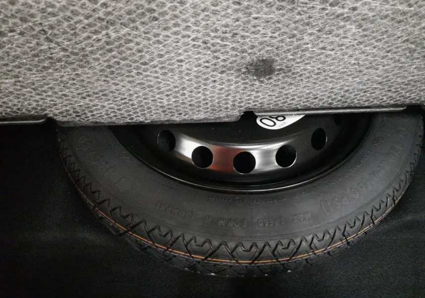 Gros plan sur la roue de secours temporaire noire sous le coffre du Renault Symbioz gris Casiopee.