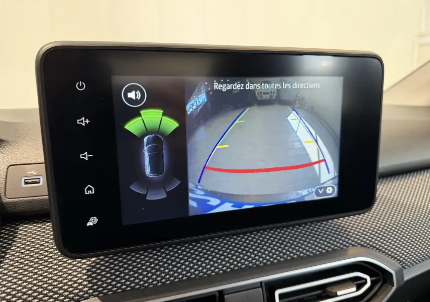 Écran central de la DACIA Sandero 2025 montrant la caméra de recul avec lignes de guidage et capteurs de proximité actifs.