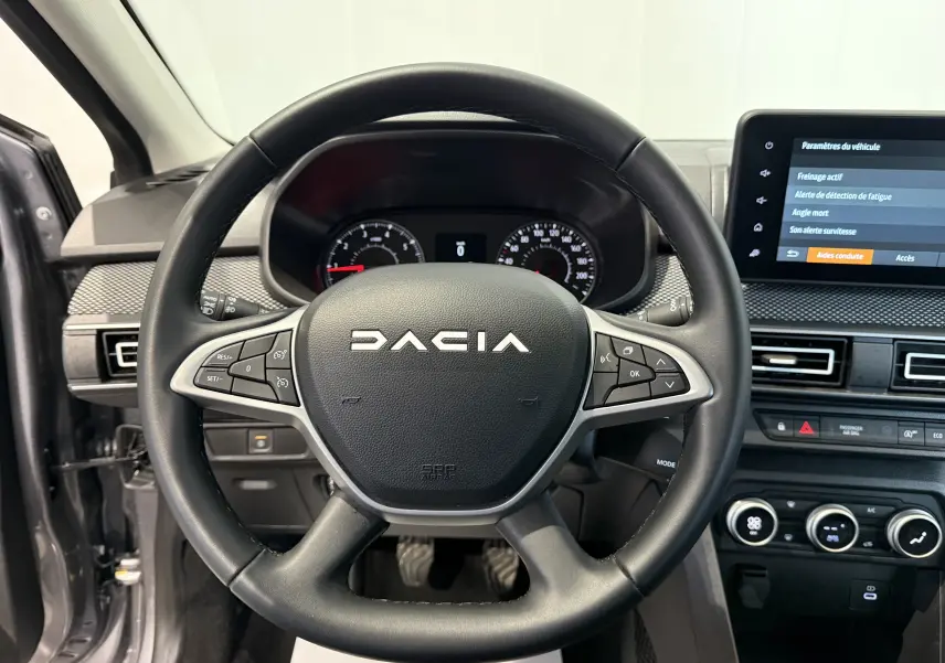 Vue rapprochée du volant noir de la Dacia Sandero 2025 avec commandes intégrées et tableau de bord numérique.