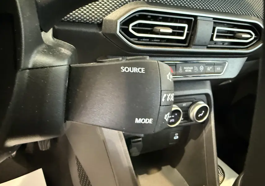 Gros plan sur la commande audio au volant côté gauche du tableau de bord noir du Dacia Sandero gris 2025.