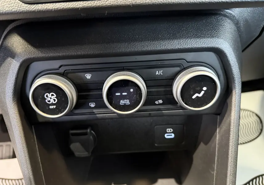 Gros plan sur les commandes de climatisation automatique de la Dacia Sandero gris, avec réglages ventilateur et air conditionné.