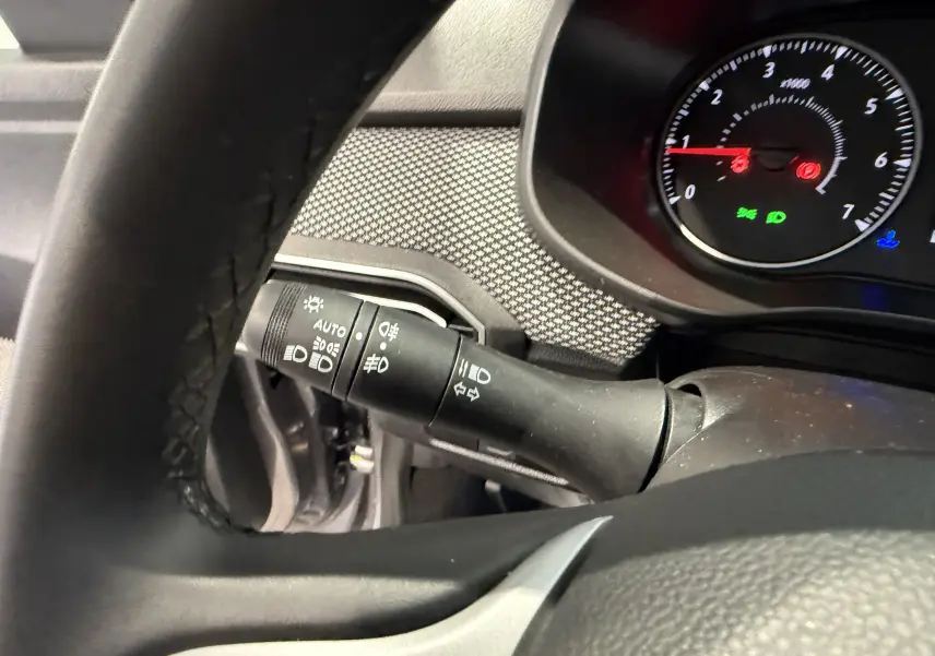 Gros plan sur la manette des feux et clignotants côté gauche du tableau de bord de la Dacia Sandero gris 2025.
