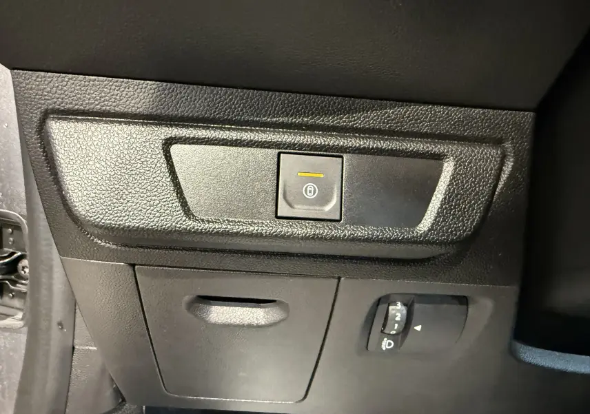 Détail du panneau de commande intérieur noir du Dacia Sandero 2025 avec bouton de verrouillage centralisé et réglage des phares.