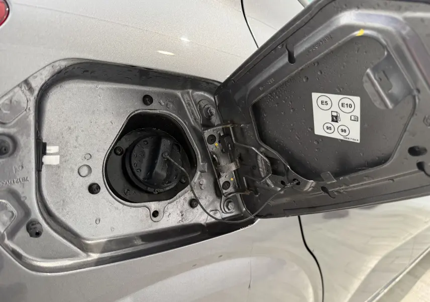 Gros plan sur la trappe à carburant ouverte côté gauche d’une Dacia Sandero gris 2025, avec bouchon essence visible.