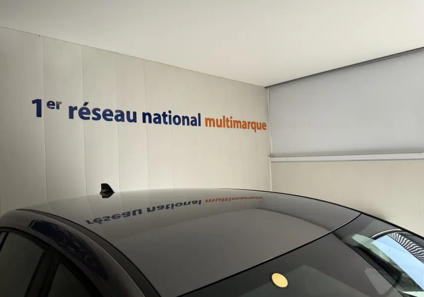 Toit gris foncé de la Dacia Sandero 2025 vu en plongée, avec antenne requin et reflet du mur blanc.