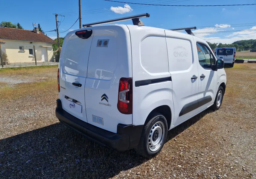 Vue 3/4 arrière droite d’un Citroën Berlingo blanc utilitaire 2020 avec barres de toit et marquage ENGIE Solutions sur la porte latérale.
