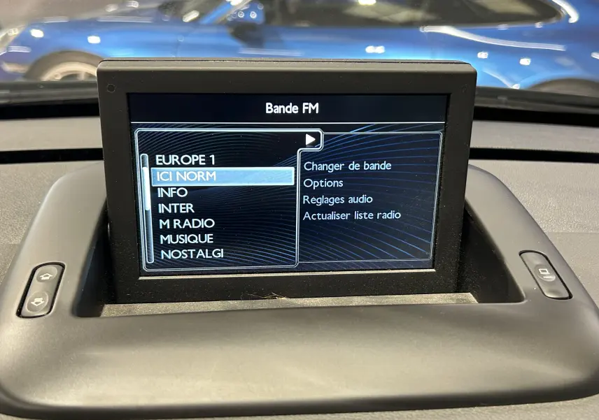 Écran central du tableau de bord affichant les options de radio FM dans une Peugeot 3008 gris, vue intérieure frontale.
