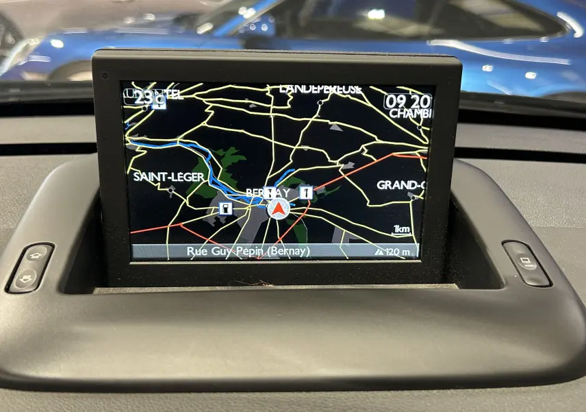 Écran GPS intégré au tableau de bord d’un Peugeot 3008 gris, affichant une carte routière en intérieur.