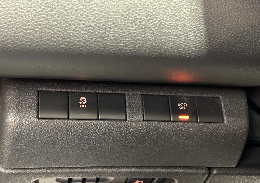 Gros plan sur les boutons de commande intérieurs du tableau de bord du Peugeot 3008 gris, avec voyants Eco et contrôle de stabilité désactivés.