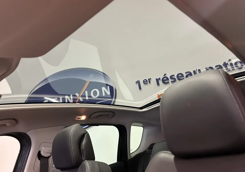 Vue intérieure du toit panoramique du Peugeot 3008 gris, avec sièges avant en cuir noir visibles de profil.