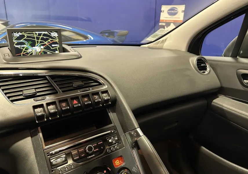 Vue intérieure côté passager du tableau de bord et console centrale d'un Peugeot 3008 gris, avec écran GPS déployé.