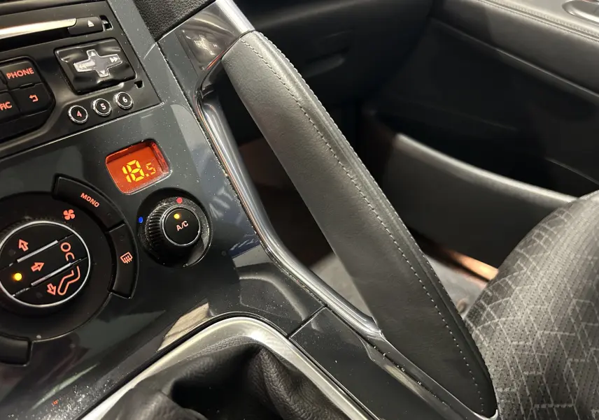 Gros plan intérieur sur le frein à main en cuir gris et la console centrale du Peugeot 3008 gris, avec commandes climatisation visibles.