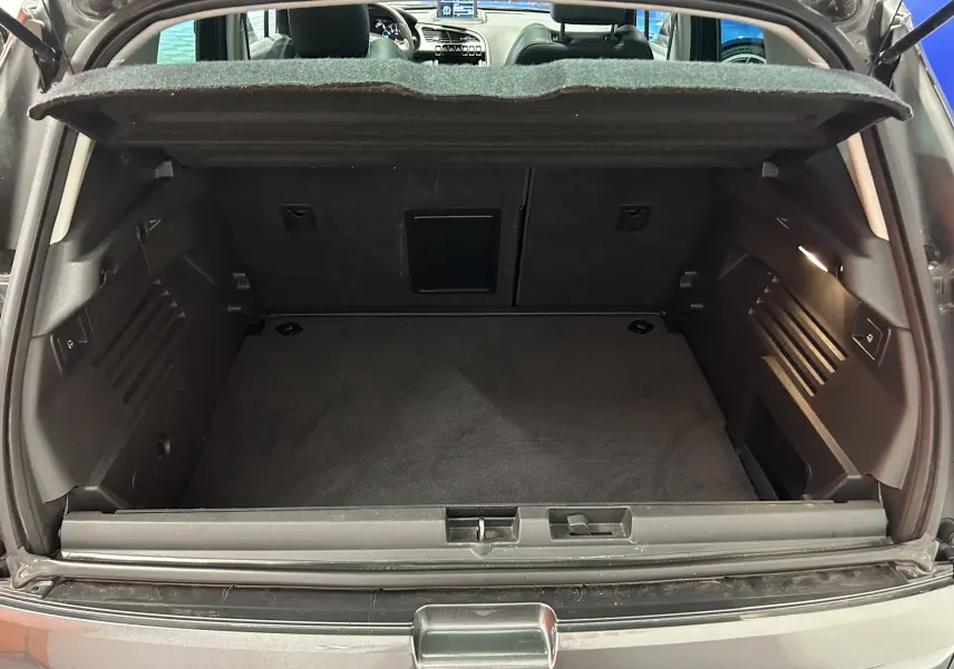 Coffre ouvert vu de l'arrière d'un Peugeot 3008 gris, montrant un espace de chargement propre et bien agencé.