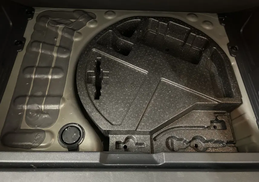 Coffre à outils vide dans le compartiment de roue de secours d'un Peugeot 3008 gris, vue de dessus.
