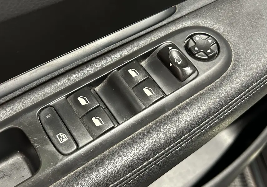 Détail des commandes de lève-vitres et réglage des rétroviseurs sur la porte côté conducteur du Peugeot 3008 gris.