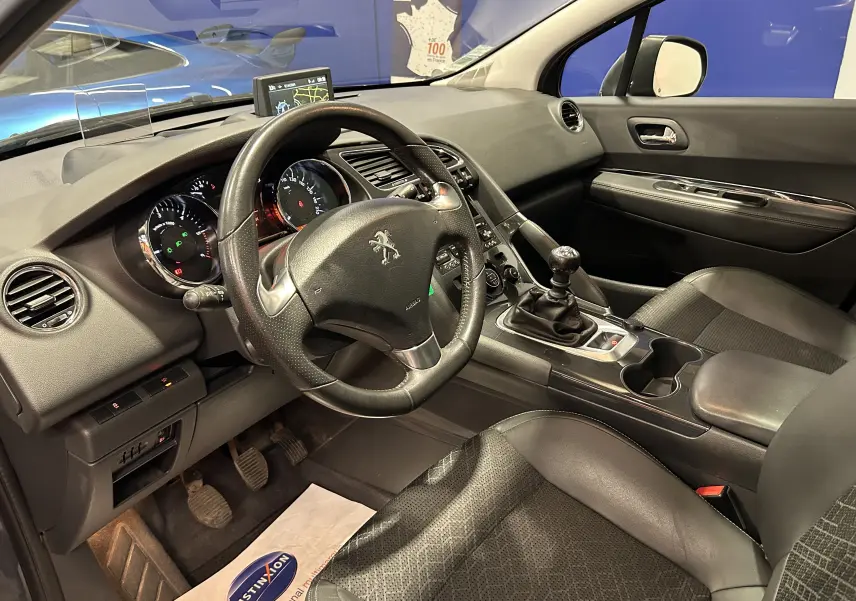 Vue intérieure côté conducteur du Peugeot 3008 gris de 2015, montrant le volant, tableau de bord et levier de vitesses manuel.
