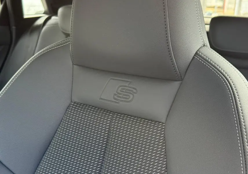 Gros plan sur le siège avant sport gris avec logo S embossé, intérieur Audi A3 Sportback 2025.