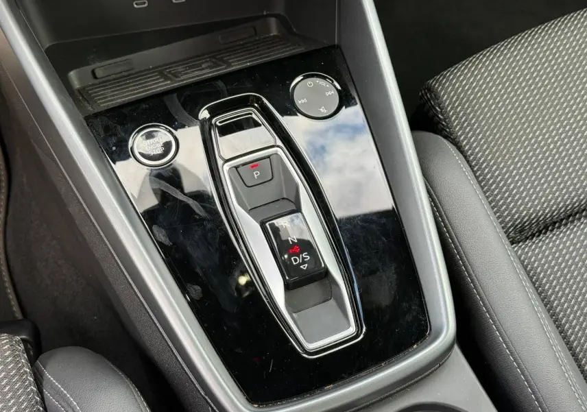 Gros plan sur la console centrale noire brillante avec sélecteur de boîte automatique et tissu gris du siège Audi A3 Sportback.