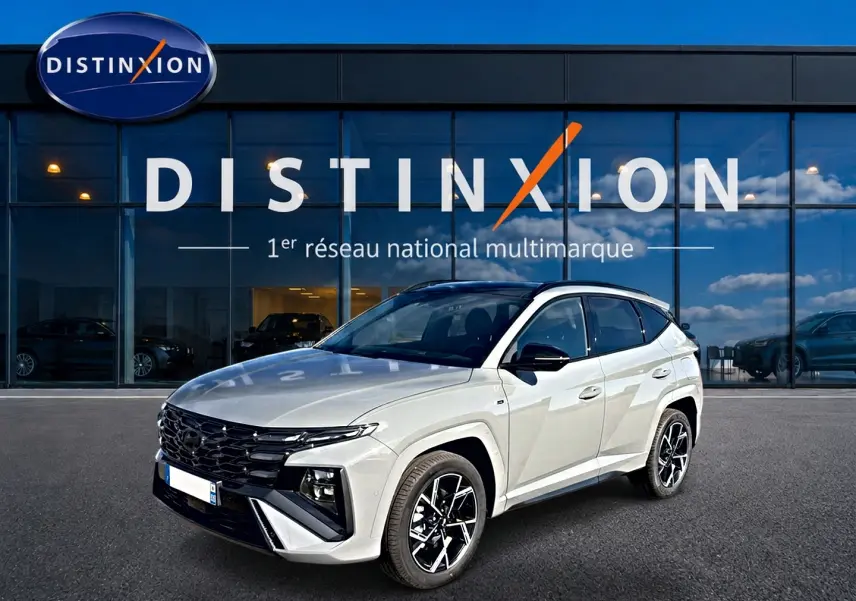 Hyundai Tucson 1.6 T-GDI hybride gris shadow en 3/4 avant droit, avec calandre noire et jantes alu distinctives.