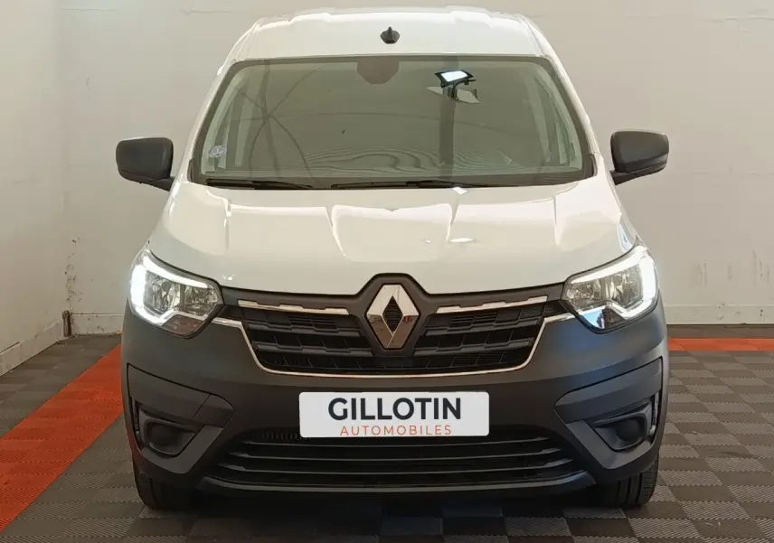 Vue frontale d’un Renault Express blanc avec phares allumés et pare-chocs noir mat dans un garage.
