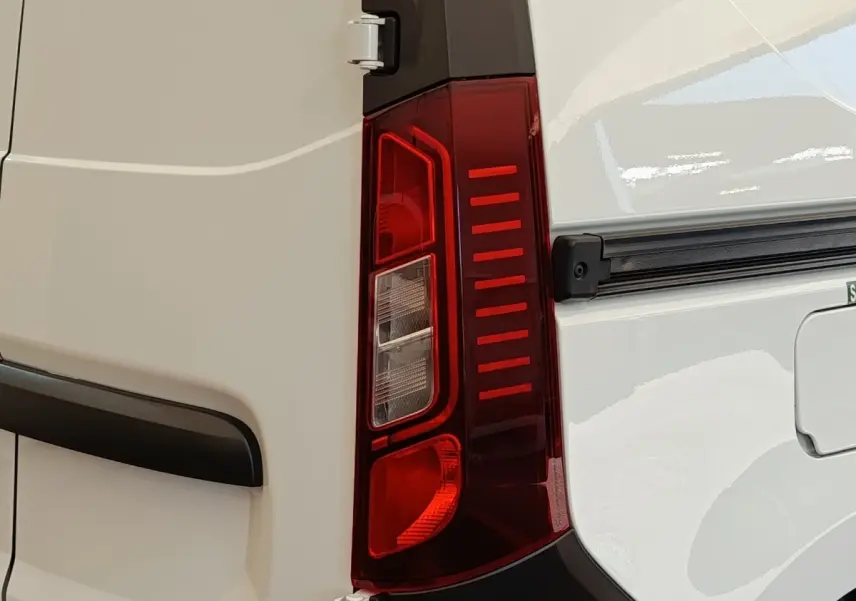 Gros plan sur le feu arrière droit rouge du Renault Express blanc, avec partie de la porte arrière visible.