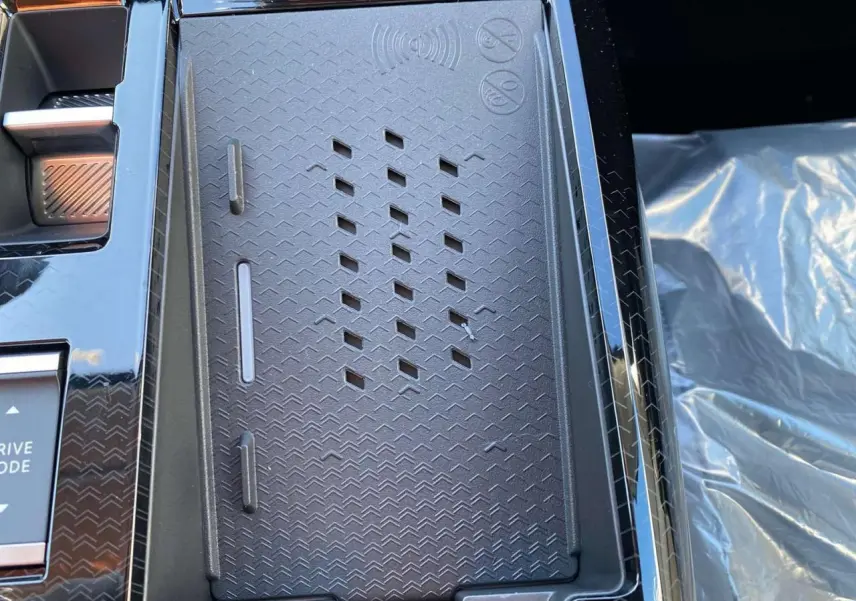Détail du chargeur sans fil noir au centre de la console du Citroën C5 Aircross 2026, intérieur moderne.