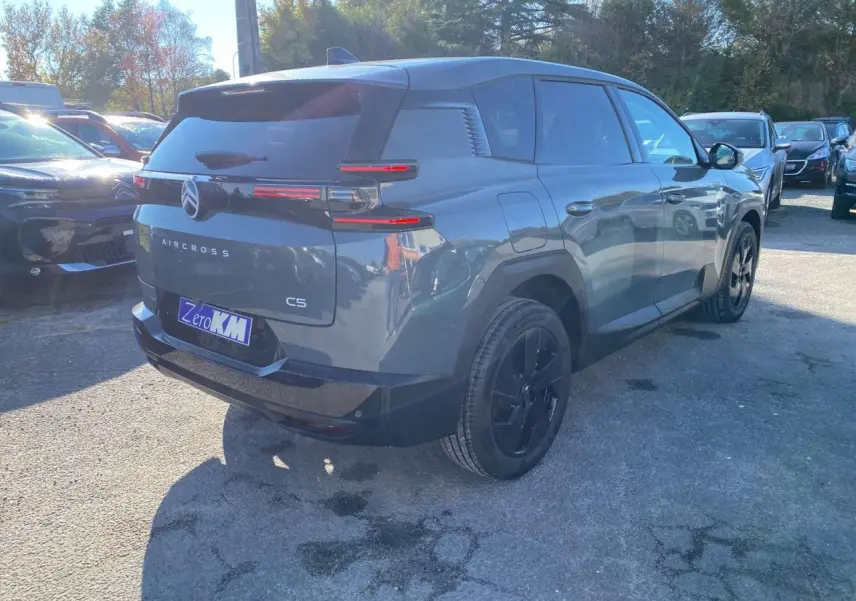 Vue 3/4 arrière droite d'un Citroën C5 Aircross vert métallisé avec jantes alliage noires sur parking en extérieur.