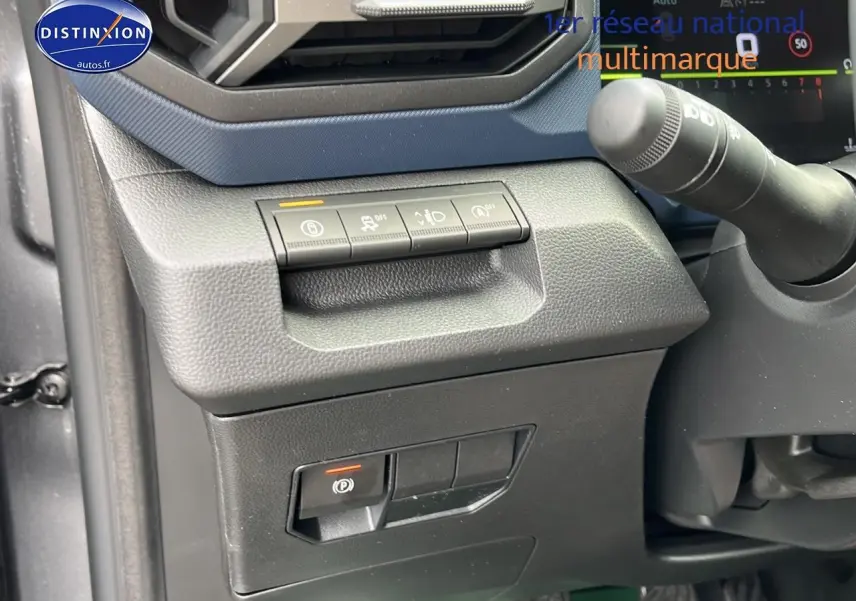 Détail du tableau de bord côté gauche du Dacia Duster gris schiste, avec commandes d'assistance et frein à main électrique.