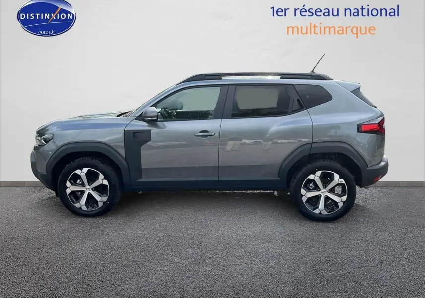 Profil droit du Dacia Duster gris schiste 2025 avec jantes alu et barres de toit noires visibles.