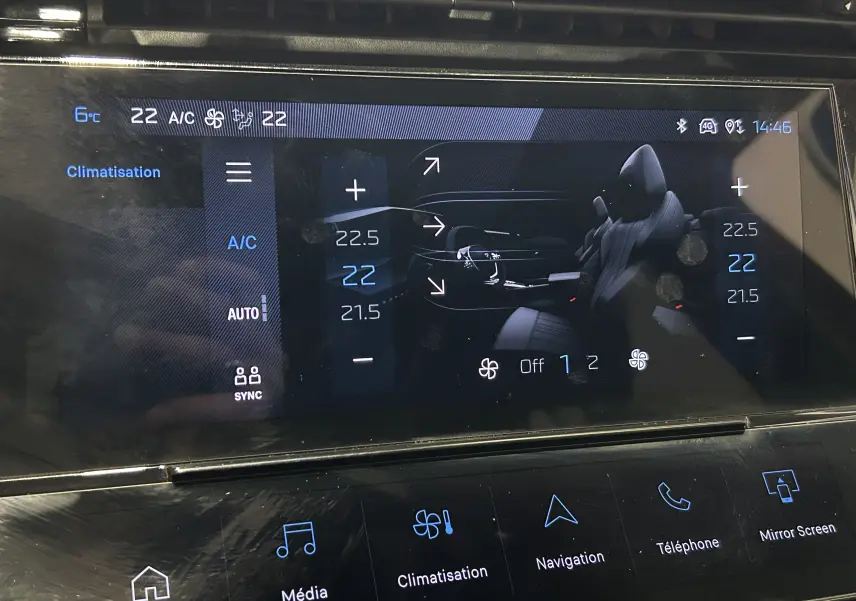 Écran tactile central de la Peugeot 308 rouge 2024 montrant les réglages de climatisation et la vue intérieure du véhicule.