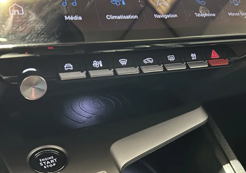 Vue rapprochée de la console centrale de la Peugeot 308 2024 rouge, avec boutons de commande et bouton start/stop visible.