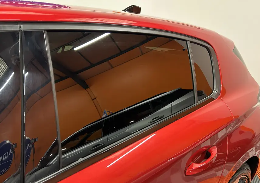 Vue latérale côté droit sur la porte arrière d’une Peugeot 308 rouge 2024 avec vitre teintée et poignée intégrée.