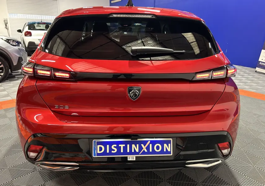 Vue arrière d'une Peugeot 308 rouge 2024 avec feux LED allumés et double sortie d'échappement chromée.