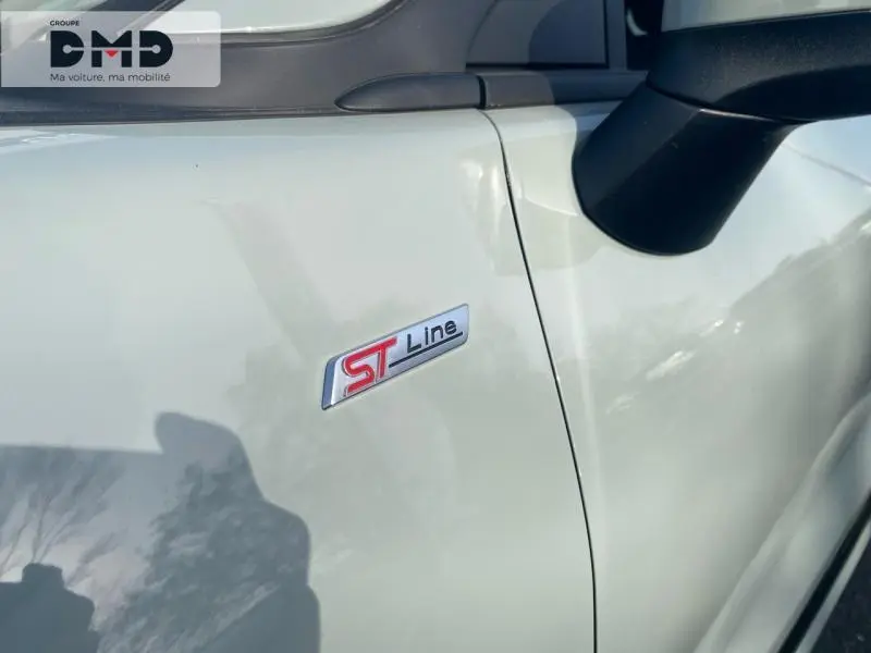 Gros plan sur l'écusson ST Line côté avant droit d'un Ford Puma gris Cactus avec rétroviseur noir.