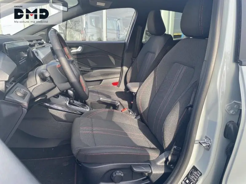 Intérieur avant droit de la Ford Puma 2026 avec sièges tissu gris à surpiqûres rouges et volant multifonction.