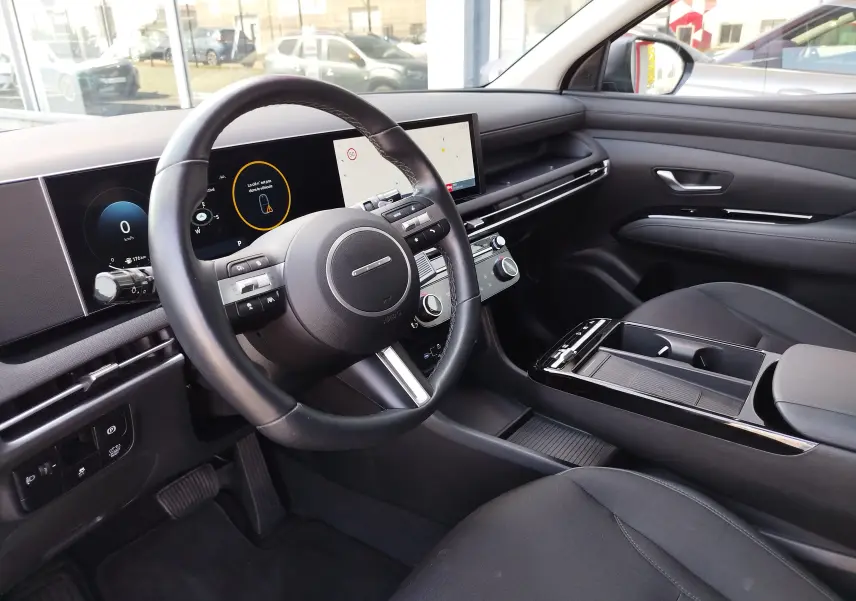 Vue intérieure côté conducteur du Hyundai Tucson 2024, tableau de bord moderne avec écran tactile et volant multifonction noir.