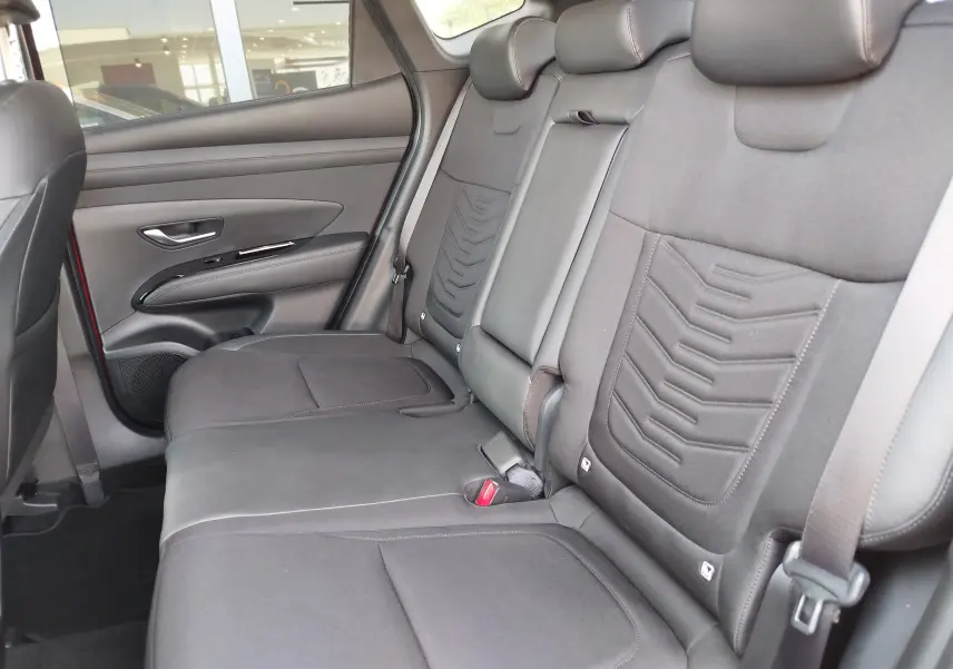 Vue intérieure côté droit des sièges arrière gris foncé du Hyundai Tucson 2024, avec appuie-têtes et ceintures visibles.