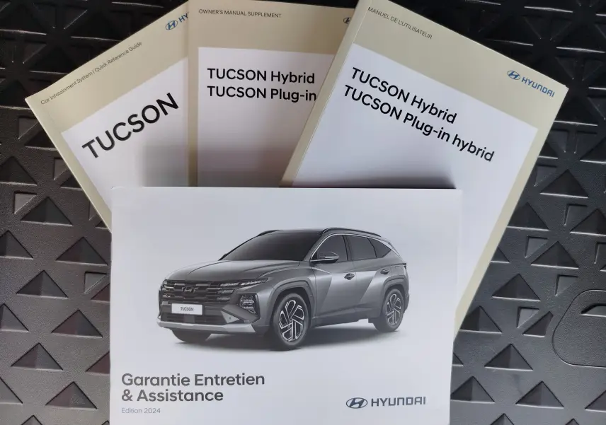 Image montrant plusieurs manuels Hyundai Tucson 2024 avec une photo du SUV gris en 3/4 avant sur la couverture Garantie Entretien.