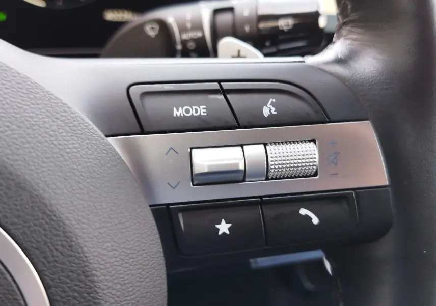 Gros plan sur les commandes au volant côté gauche du Hyundai Tucson 2024, boutons mode, volume et appel visibles.
