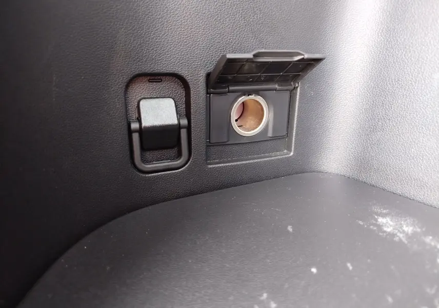Prise 12V avec cache ouvert et crochet d’arrimage dans le coffre d’un Hyundai Tucson 2024.