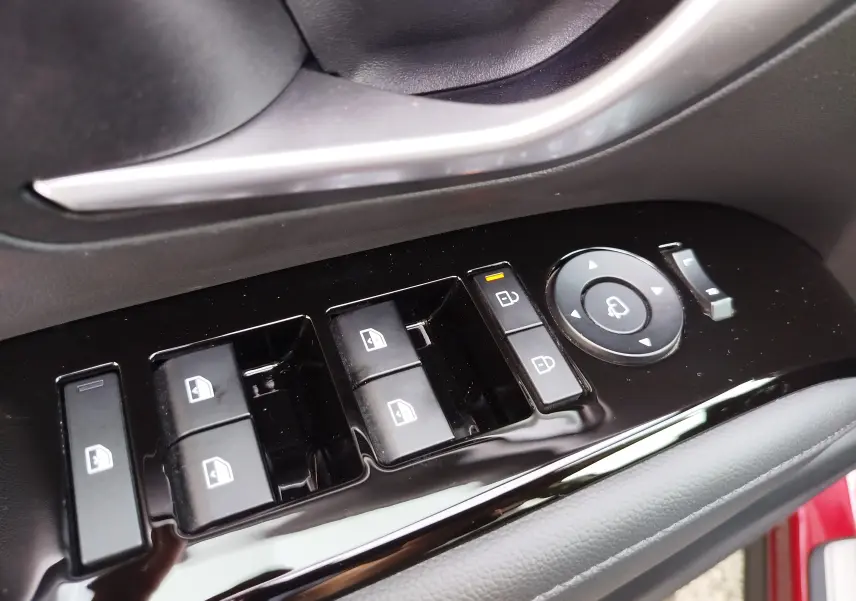 Gros plan sur les commandes de lève-vitres et rétroviseurs côté conducteur du Hyundai Tucson 2024 en rouge Ultimate Red Métal.