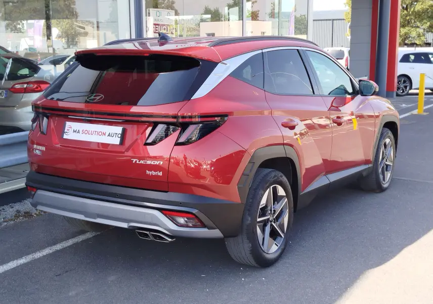 Vue 3/4 arrière droite du Hyundai Tucson 2024 hybride en rouge Ultimate Red Métal avec feux LED et jantes bi-ton.