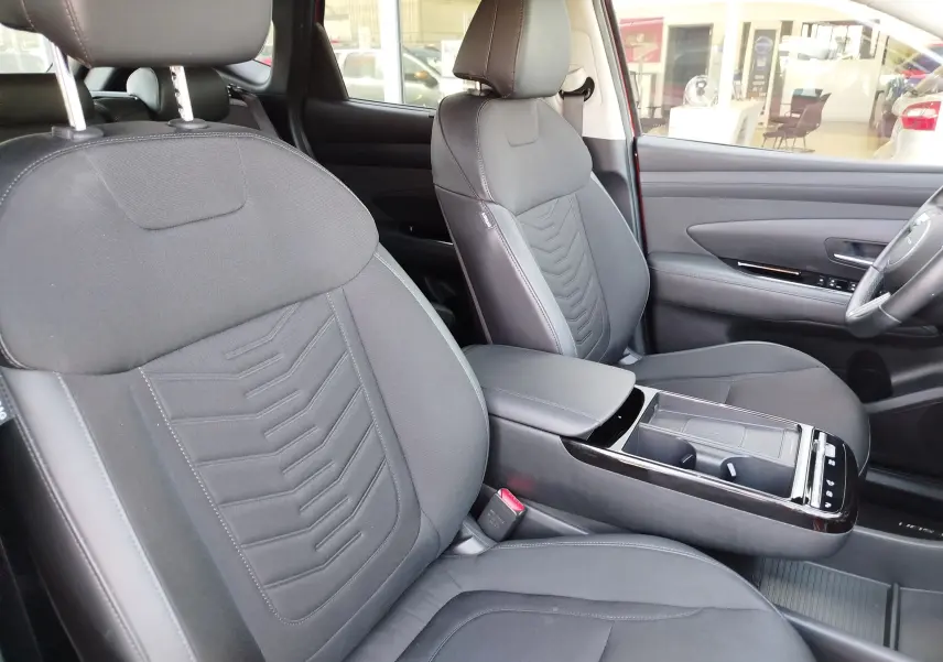 Vue intérieure du Hyundai Tucson 2024, sièges avant noirs avec console centrale et détails modernes visibles.