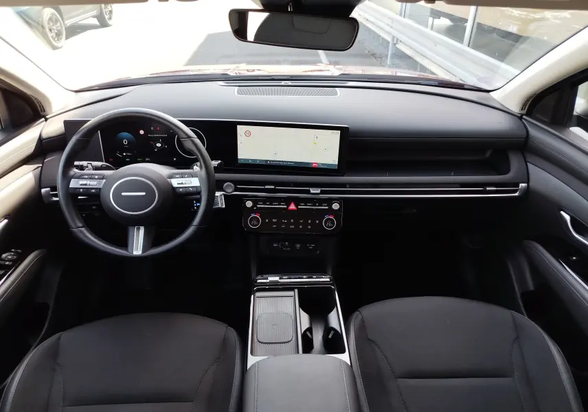 Vue intérieure avant du Hyundai Tucson 2024, tableau de bord noir avec écran tactile et volant multifonction.