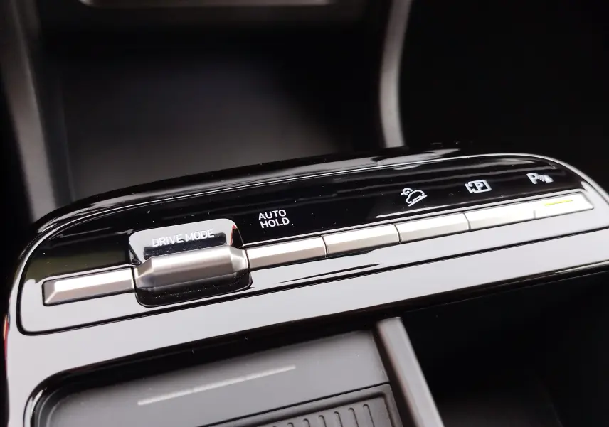 Gros plan sur les commandes de la console centrale du Hyundai Tucson 2024, finition noire brillante avec boutons argentés.