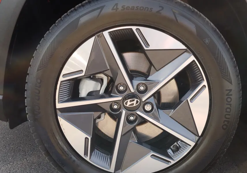 Gros plan sur la roue avant droite du Hyundai Tucson 2024, jante alliage bicolore au design géométrique.