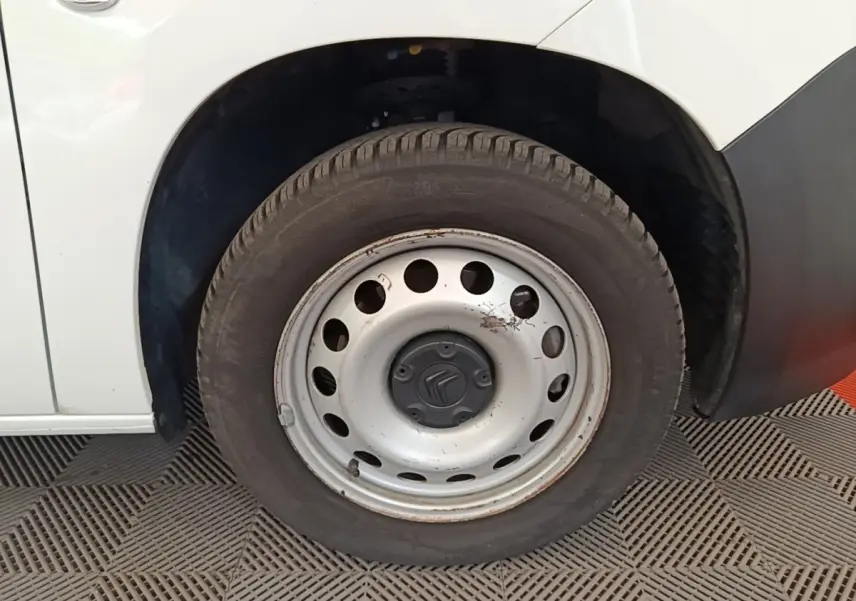 Gros plan sur la roue avant gauche en jante acier du Citroën Berlingo XL blanc, avec carrosserie visible en arrière-plan.