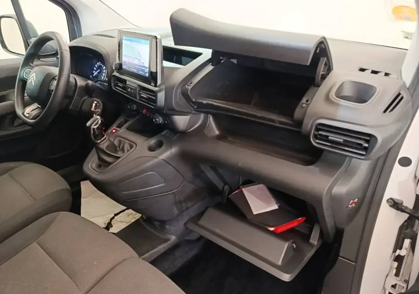 Vue intérieure côté passager du Citroën Berlingo XL blanc, montrant tableau de bord et rangements ouverts.