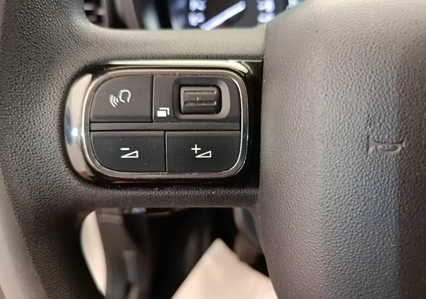 Gros plan sur les commandes multifonctions du volant noir du Citroën Berlingo XL blanc de 2020.